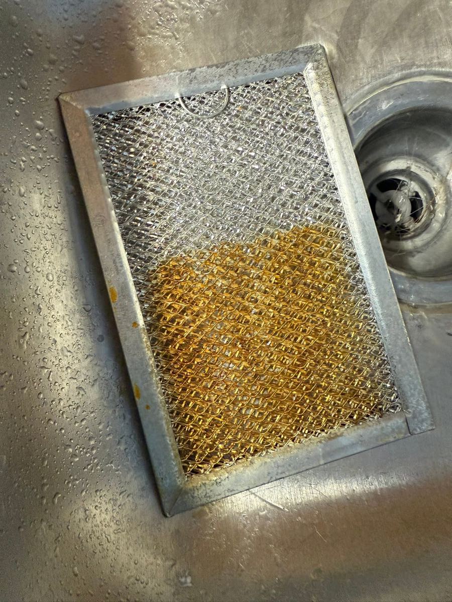 Range-hood filter part-way through degreasing, grease on one half and clean metal on the other